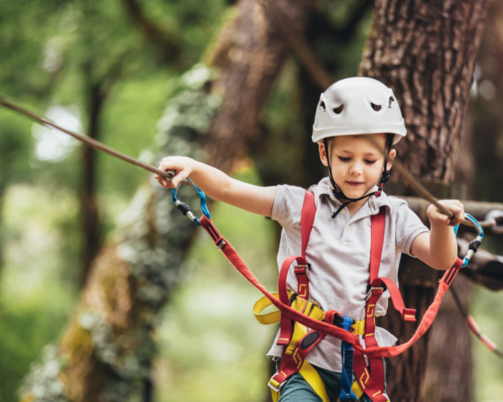 Happy child enjoying activity in a climbing adventure park on a Happy child enjoying activity in a climbing adventure park on a